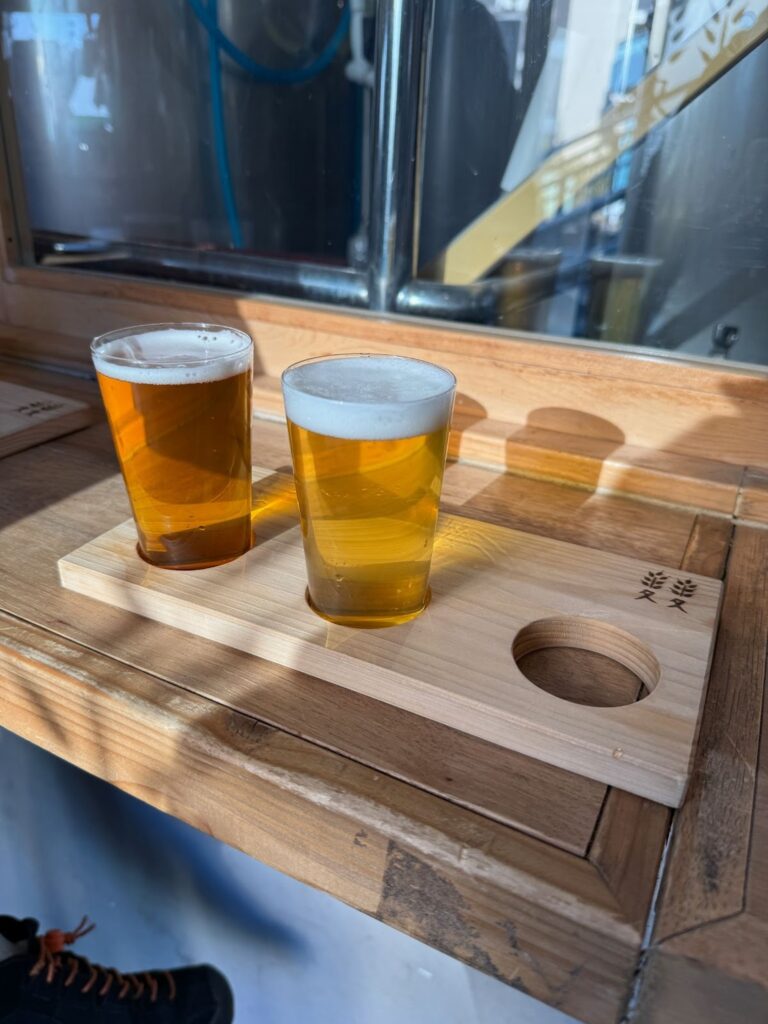 ふたこビールのタップルームにて、木製のトレイに乗せられた2つのグラスに注がれた黄金色のクラフトビール